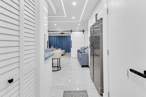 A modern kitchen with a refrigerator, a dining area with a table and chairs, and a living area with a sofa. - Stunning Designer Studio with Luxury Finishes (Deerfield Beach)
