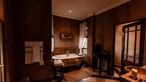 Une salle de bain avec une baignoire sur pieds, un porte-serviettes, un lavabo et un miroir.