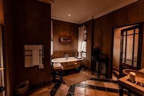A bathroom with a freestanding bathtub, a towel rack, a sink, and a mirror.