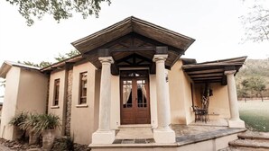 Un bâtiment doté d’une façade en pierre, d’une porte en bois et d’un porche couvert avec des colonnes.