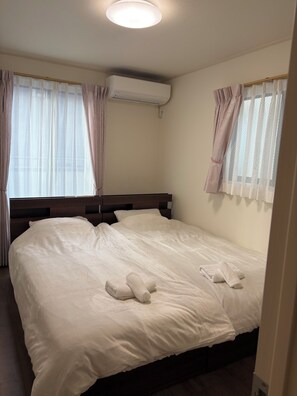 A hotel room with a bed, curtains, an air conditioning unit, and a ceiling light. - 2-Min Walk to Koya Station | Brand-New 4BR Private House | Free Parking & Wi-Fi (足立区)