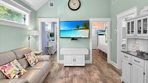 A living room with a sofa, TV, and kitchen area. - Seaglass Village 224 - Windswept (Wells)