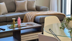 Una sala de estar moderna con un sofá, una mesa de centro de vidrio y una mesita auxiliar.