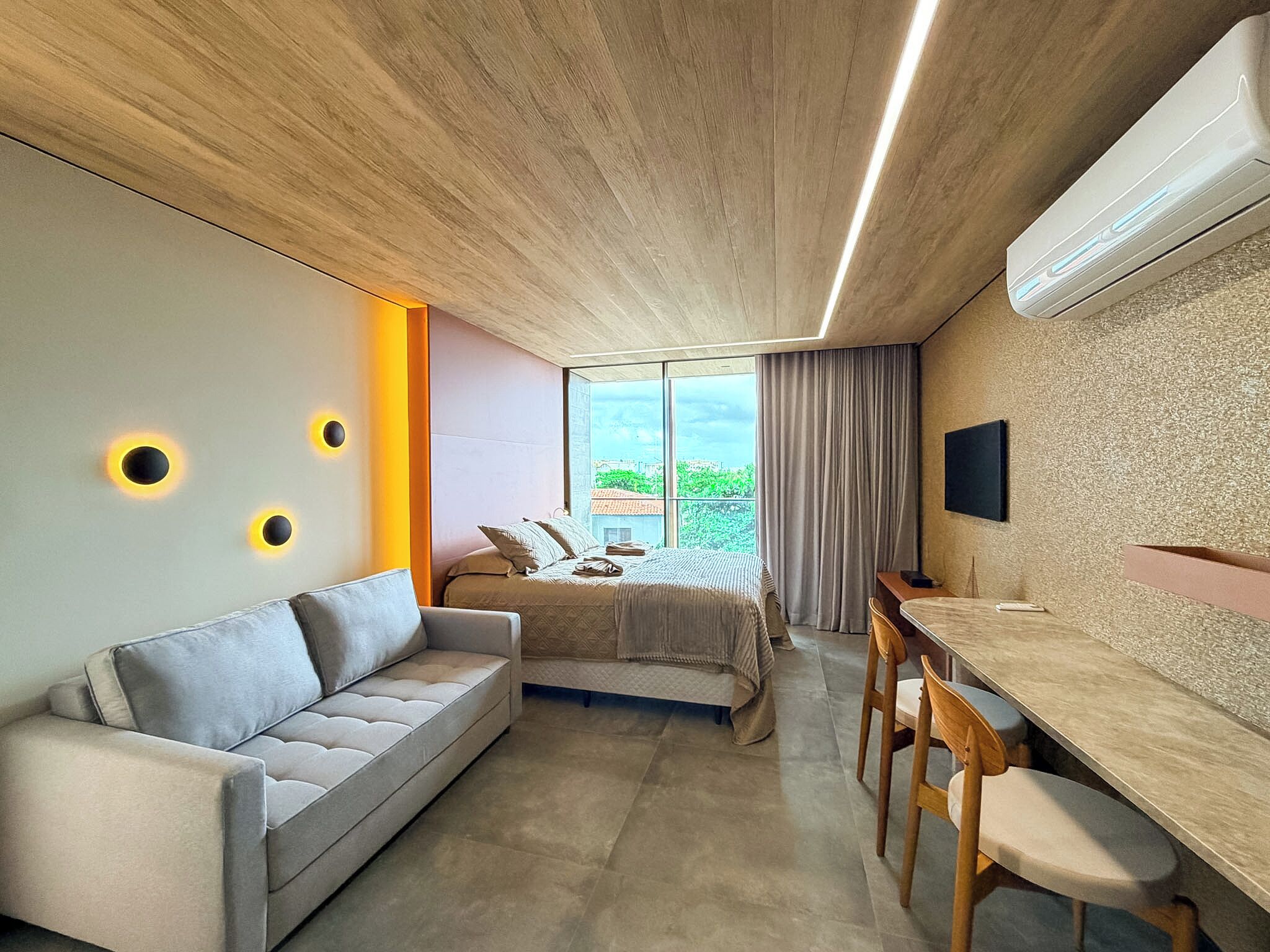 A modern bedroom with a bed, a sofa, a desk, and a TV.