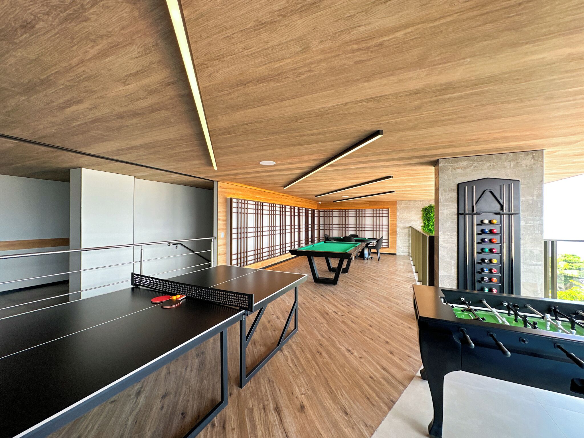 A modern indoor recreational area with ping pong tables, a foosball table, and a pool table.