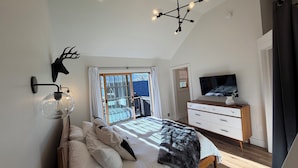 Een slaapkamer met een bed, een televisie, een dressoir en een plafondlamp.
