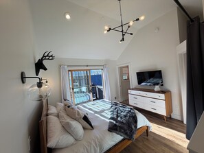 Ein Schlafzimmer mit einem Bett, einem Fernseher, einem Schminktisch und einer Deckenleuchte.