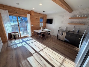 Un intérieur en bois comprenant un coin repas, une cuisine et de grandes fenêtres.