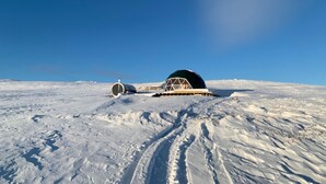 A snow-covered landscape with a dome-shaped structure and a cylindrical object.