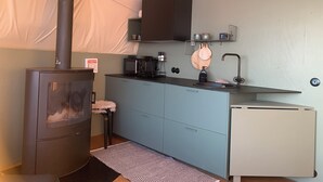 A compact kitchen with a wood stove, a small refrigerator, and a sink.