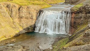 A waterfall in a natural setting with a river flowing through a valley.