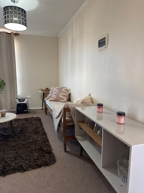 Une chambre à coucher de taille réduite, comprenant un lit, une table de chevet et un petit bureau avec une lampe.