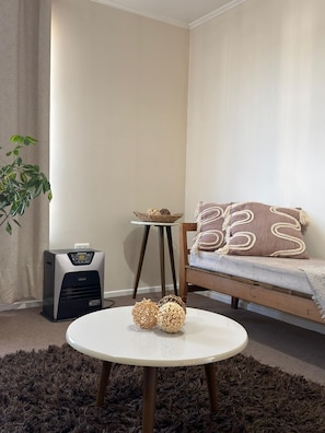 Un salon avec une table ronde, un canapé, un radiateur et une plante.