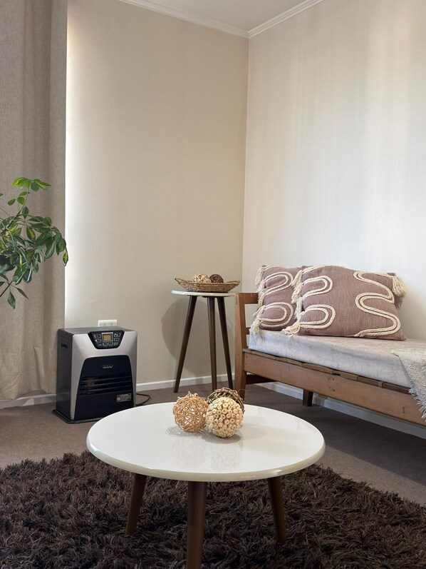 Un salon avec une table ronde, un canapé, un radiateur et une plante.