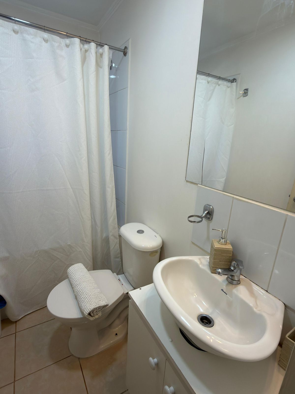 A bathroom with a toilet, bidet, sink, and a mirror.