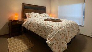 A bedroom with a bed, bedside lamps, a nightstand, a window, and a ceiling light.