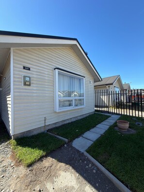 A single-story mobile home with a large window, a small porch, and a fenced yard. - El Rincon de Paz, House equipped at 11 km airport (Puerto Montt)
