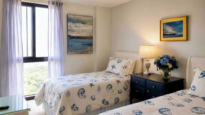 A bedroom with two beds, a nightstand, a lamp, and a window with curtains. - Stunning 3-bedroom condo 
Labor Day Special, book now! (Destin)
