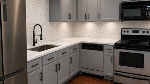 A kitchen with grey cabinets, a stainless steel refrigerator, a black microwave, a dishwasher, and a stove. - Stunning 3-bedroom condo 
Labor Day Special, book now! (Destin)