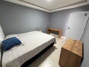 Ein Schlafzimmer mit Bett, Bank, Tür und einem kleinen Holztisch.