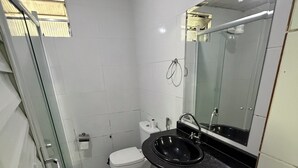 A bathroom with a toilet, sink, and glass shower enclosure. - Cozy house in Belém, close to everything, pets allowed. (Belém)