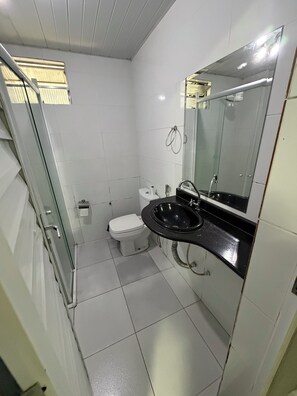 A bathroom with a toilet, sink, and glass shower enclosure. - Vrbo Property (Belém)