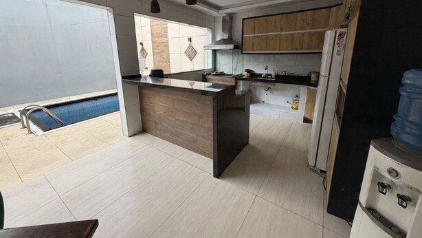 A modern kitchen with a central island, a built-in stove, and a large water dispenser. - Cozy house in Belém, close to everything, pets allowed. (Belém)