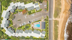 An aerial view of a coastal hotel with multiple buildings, a parking lot, a swimming pool, and a beach. - Steps to Sugar Beach | 2 King Beds, Pool, Hot Tub & AC in North Kihei (Kihei)