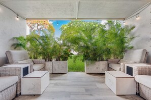 A covered outdoor seating area with wicker furniture and planters, a clear view of the sky, and a grassy background. - 2BR Kihei Condo | Walk to Sugar Beach, Pool, Hot Tub & 2 King Beds (Kihei)