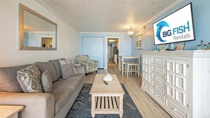 Ein Wohnzimmer mit einer Couch, einem Couchtisch und einem Fernseher, der 'BIG FISH Rentals' anzeigt.