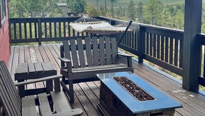 Una terraza de madera con un banco, una hamaca y una chimenea de piedra.