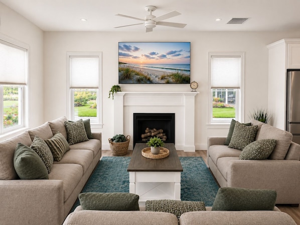 A living room with a fireplace, two sofas, a coffee table, and a ceiling fan.