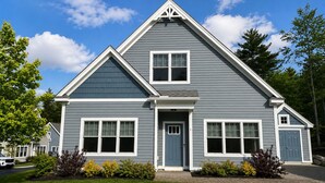 A two-story house with a gable roof, a front porch, and a garage. - Cozy cottage close to Wells & Kennebunk, Pools • Local Beaches • Family‑Friendly (Arundel)
