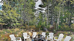 A circular outdoor seating area with a fire pit surrounded by white plastic chairs. - Cozy cottage close to Wells & Kennebunk, Pools • Local Beaches • Family‑Friendly (Arundel)