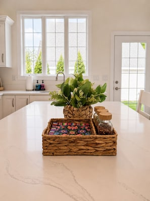 A kitchen with a large island, a window with a view of trees, and a door.