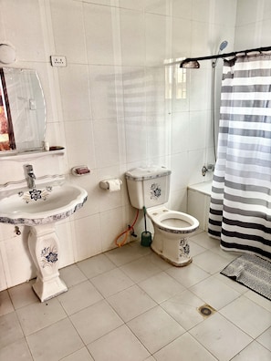 A bathroom with a sink, toilet, and shower curtain. - BLM Lodge (Monrovia)