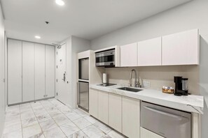 A modern kitchen with a built-in oven, microwave, and dishwasher, a sink with a faucet, and a marble countertop. - ONE OF NONE Studio @ Palms Place – 34th Floor Strip Views (Las Vegas)