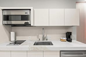 A modern kitchen with a built-in microwave, stainless steel sink, and a coffee maker.