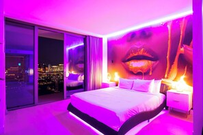 A modern hotel room with a large bed, a city view through floor-to-ceiling windows, and a unique wall mural. - ONE OF NONE Studio @ Palms Place – 34th Floor Strip Views (Las Vegas)