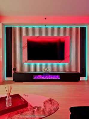 Moderni olohuone, jossa on litteänäyttöinen televisio, takka ja punainen tehosteseinä.