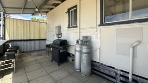 Un espacio al aire libre techado con una parrilla, asientos y tanques de propano.