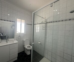 Une salle de bain comprenant des toilettes, un lavabo et un espace douche.