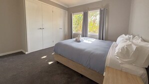 Un dormitorio con cama, armario y ventana con cortinas.
