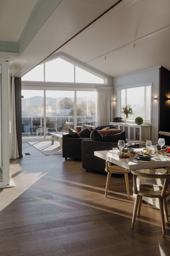 Una sala de estar moderna con un ventanal grande, una mesa de comedor para dos personas y un sofá.