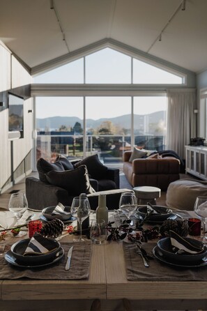 Un comedor con una mesa lista para cuatro personas, un sofá y vistas al exterior.