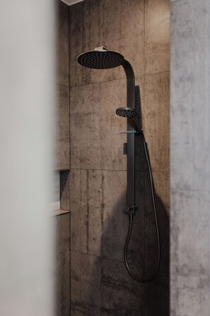 Une douche moderne au design incurvé, fixée sur un mur à texture.