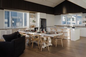 Une cuisine moderne avec un Ăźlot central, des chaises en bois et une table Ă manger pour six personnes.