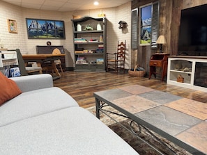 A living room with a sofa, a coffee table, a bookshelf, a television, and a fireplace.
