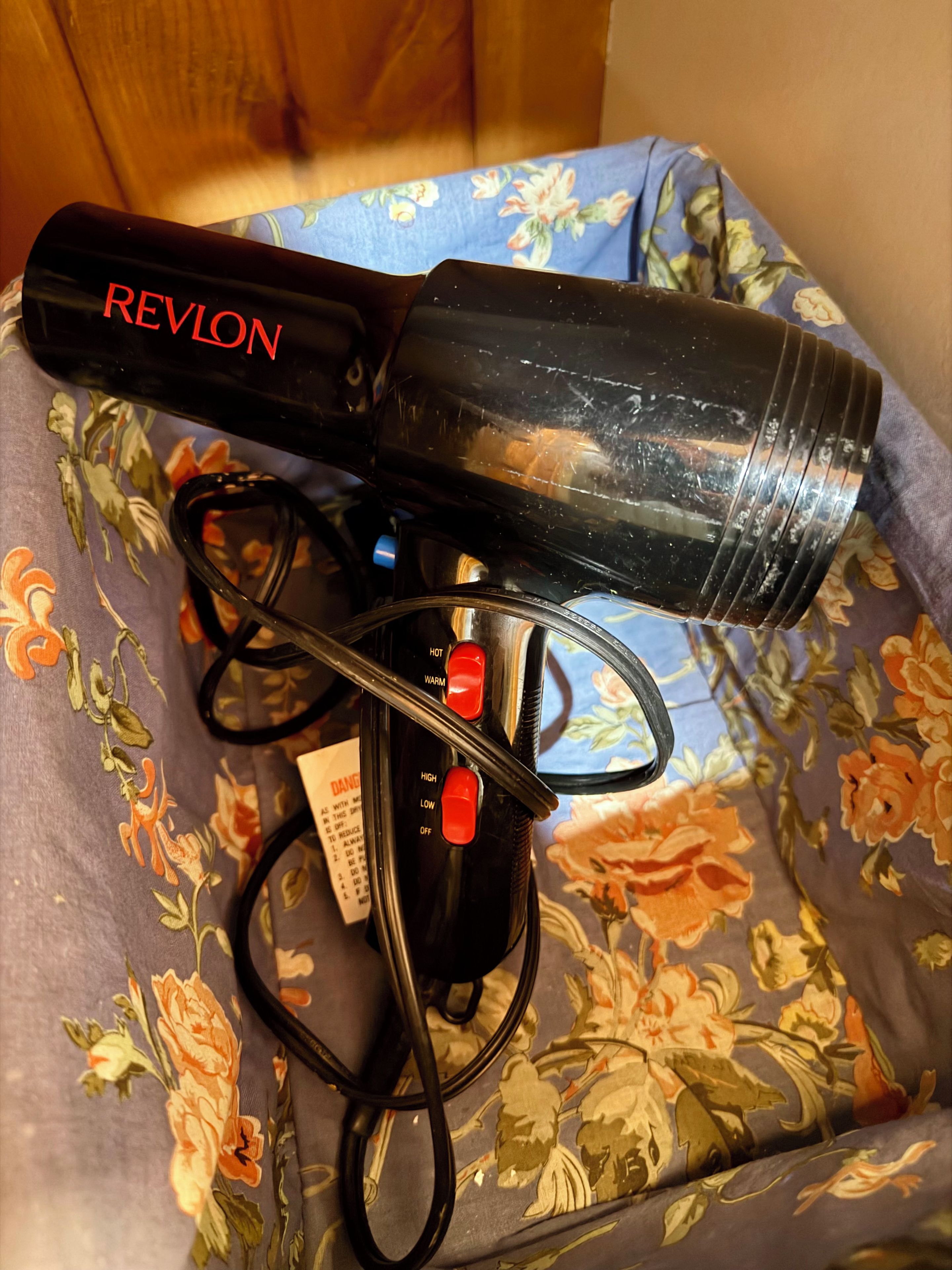 A Revlon hair dryer on a floral-patterned fabric surface.