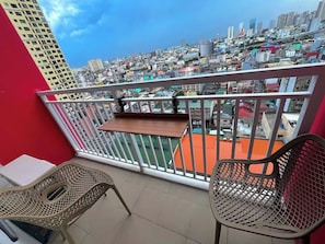 Un balcon donnant sur le paysage urbain, une table et deux chaises.